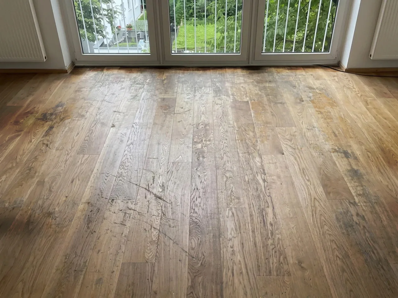 Eichen-Landhausdielen vor der Sanierung: dunkle Flecken, Kratzer und abgelaufene Oberfläche