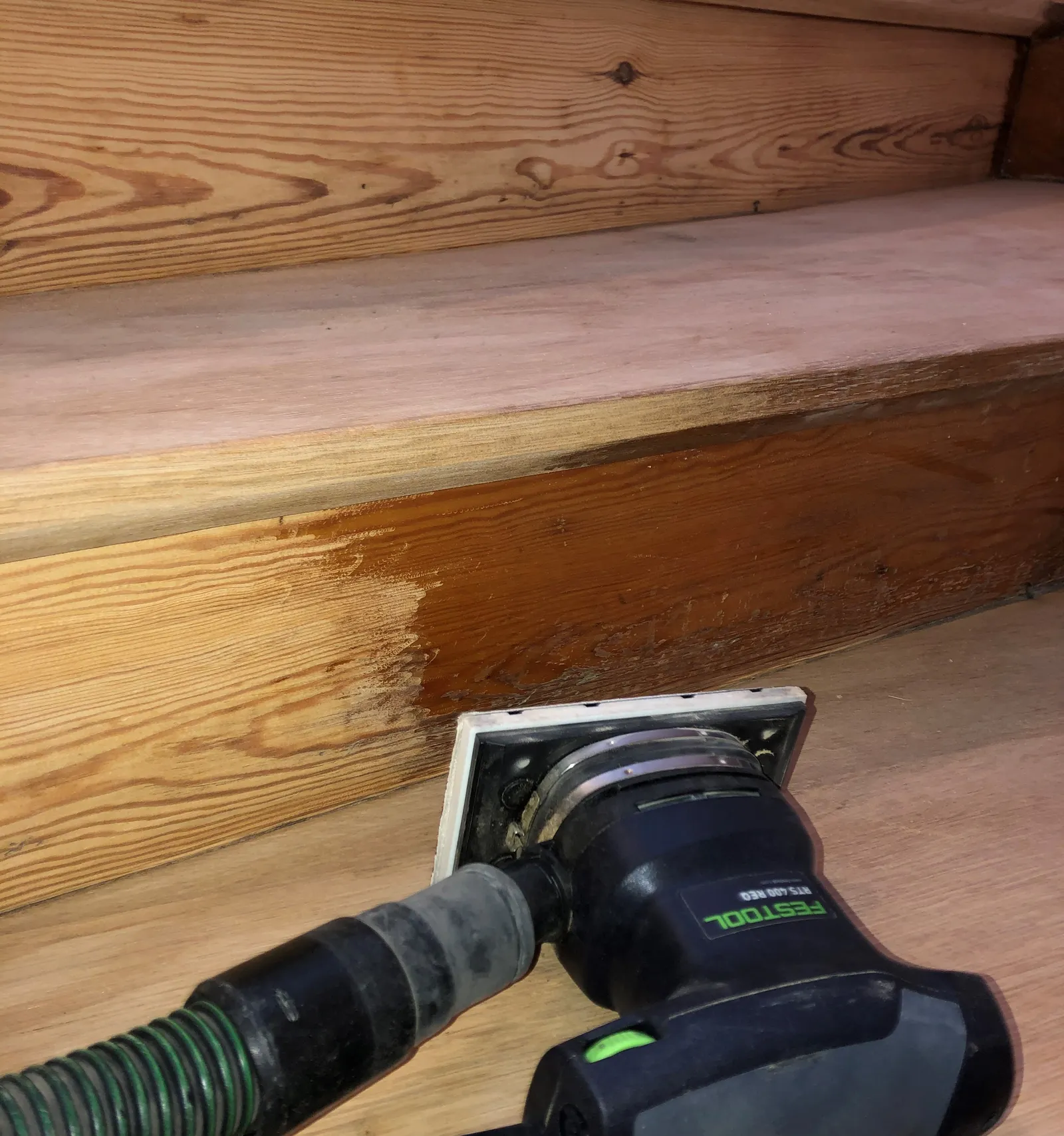 Holztreppe wird mit einem abgesaugten Handschleifer Stufe für Stufe geschliffen